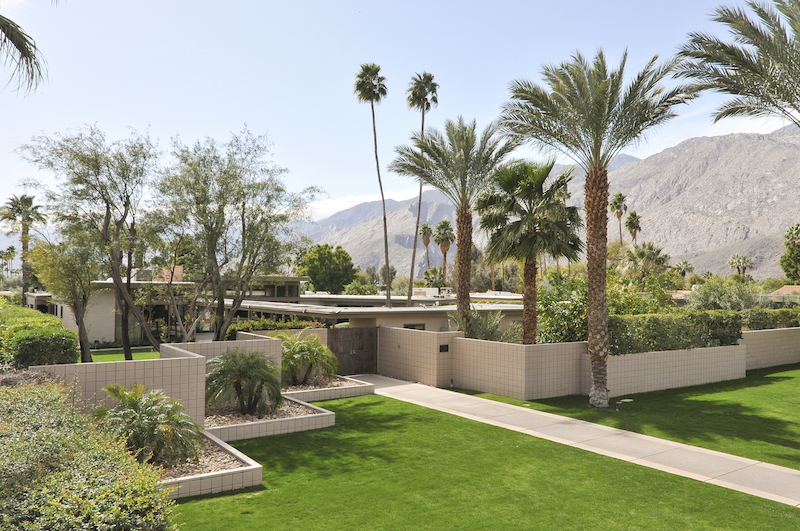 Elevated view of Frank Sinatra's home in Palm Springs from the front showing the lawn, palm trees, and mountains in background