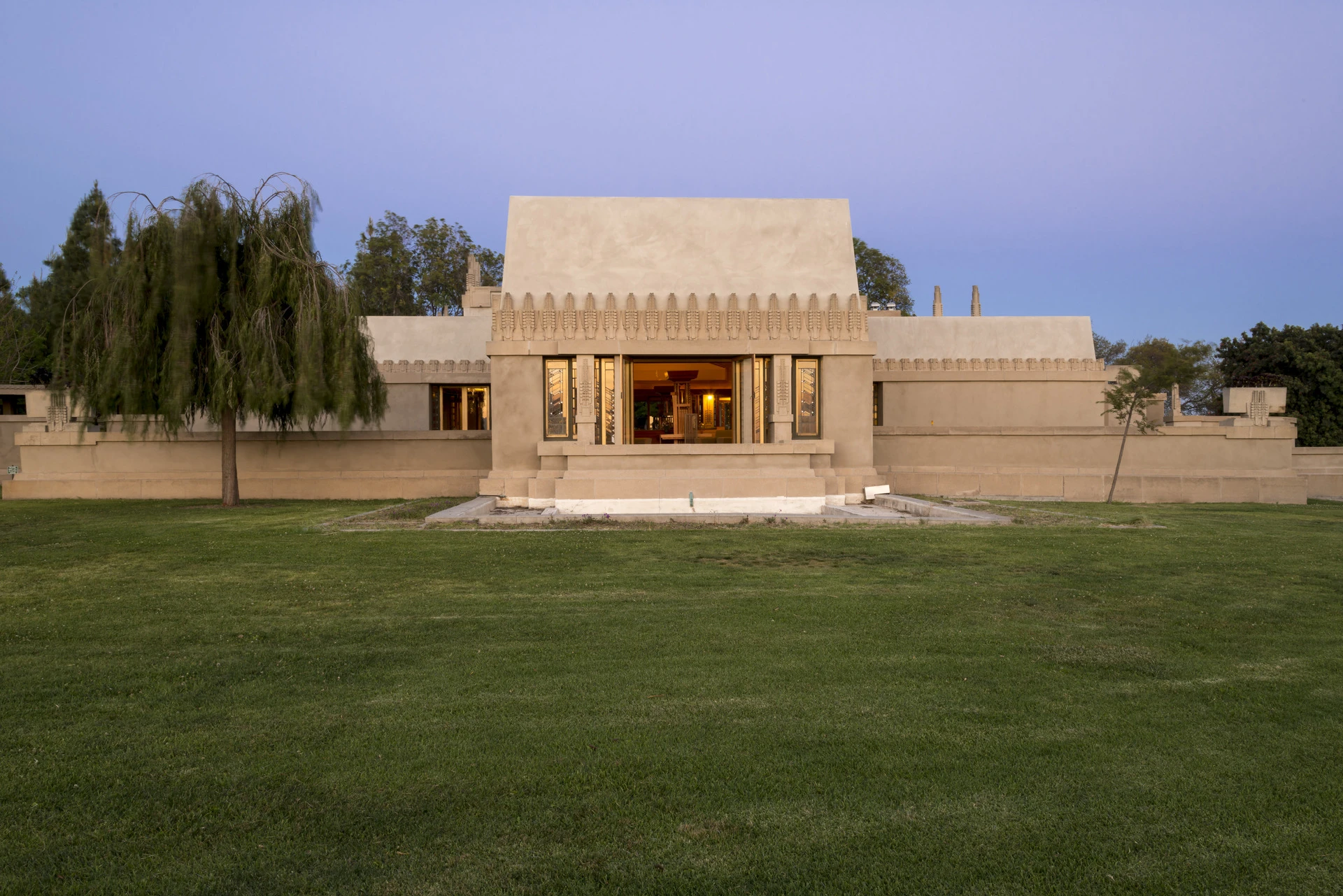 Hollyhock House west face from a distance with a green lawn