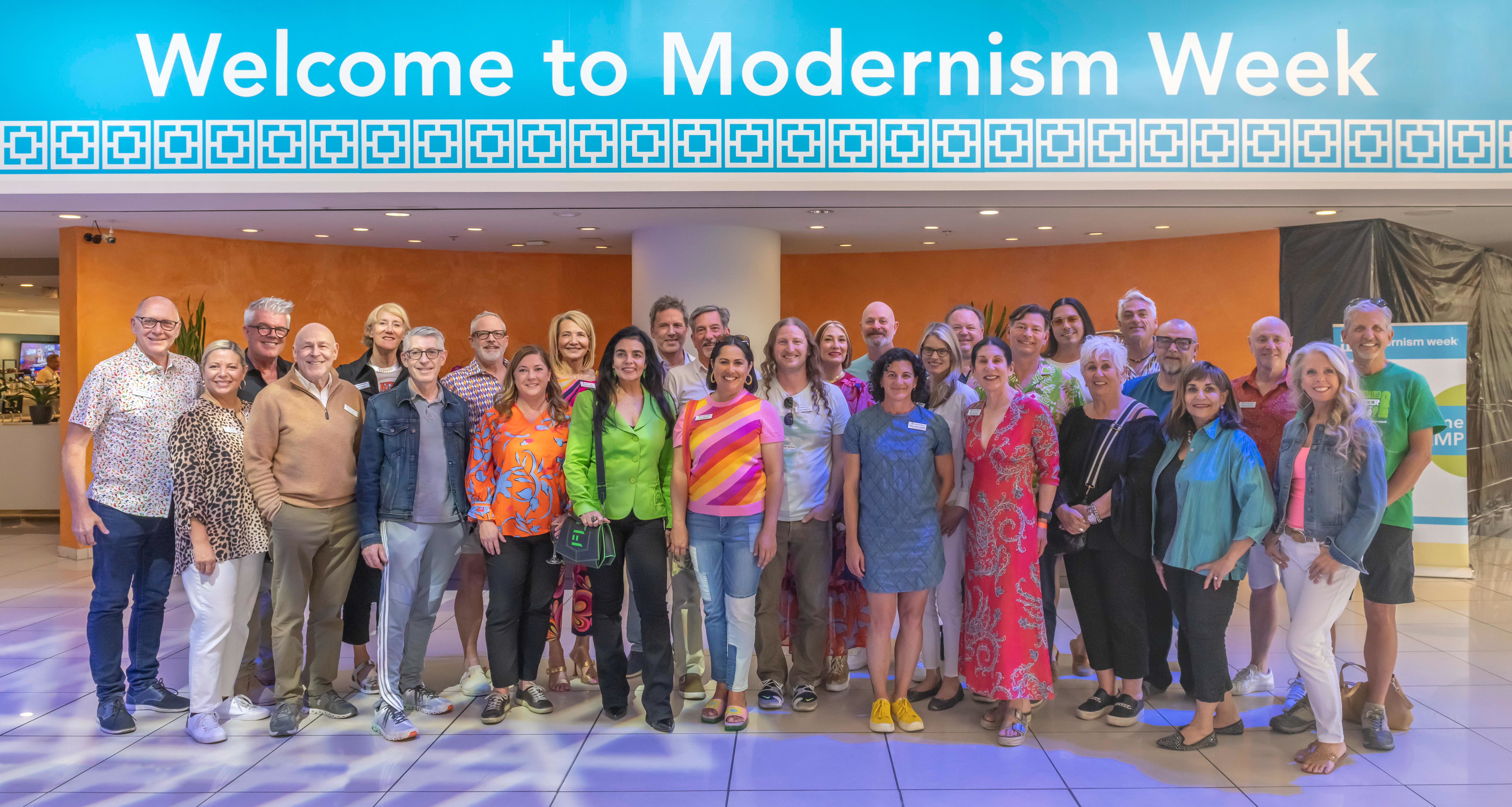 The Modernism Week team standing as a group in the lobby of the Hyatt Palm Springs under a Welcome to Modernism Week banner