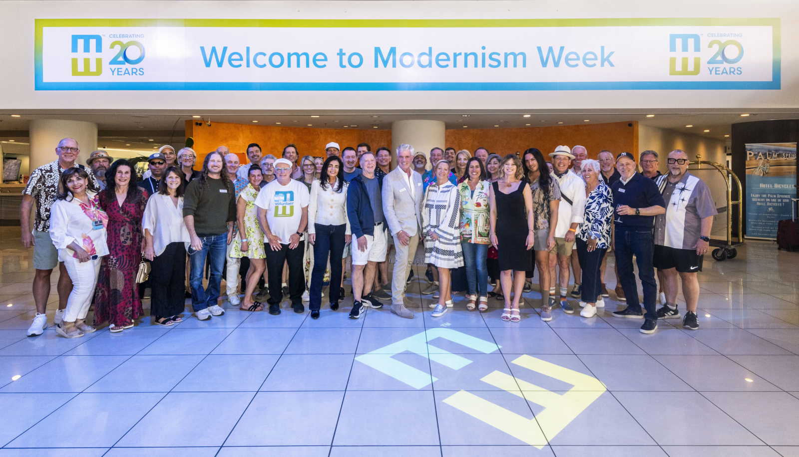 The Modernism Week team standing as a group in the lobby of the Hyatt Palm Springs under a Welcome to Modernism Week banner