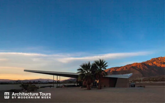 The Palm Springs Visitor Center with mountains, palm trees, and blue sky at sunrise
