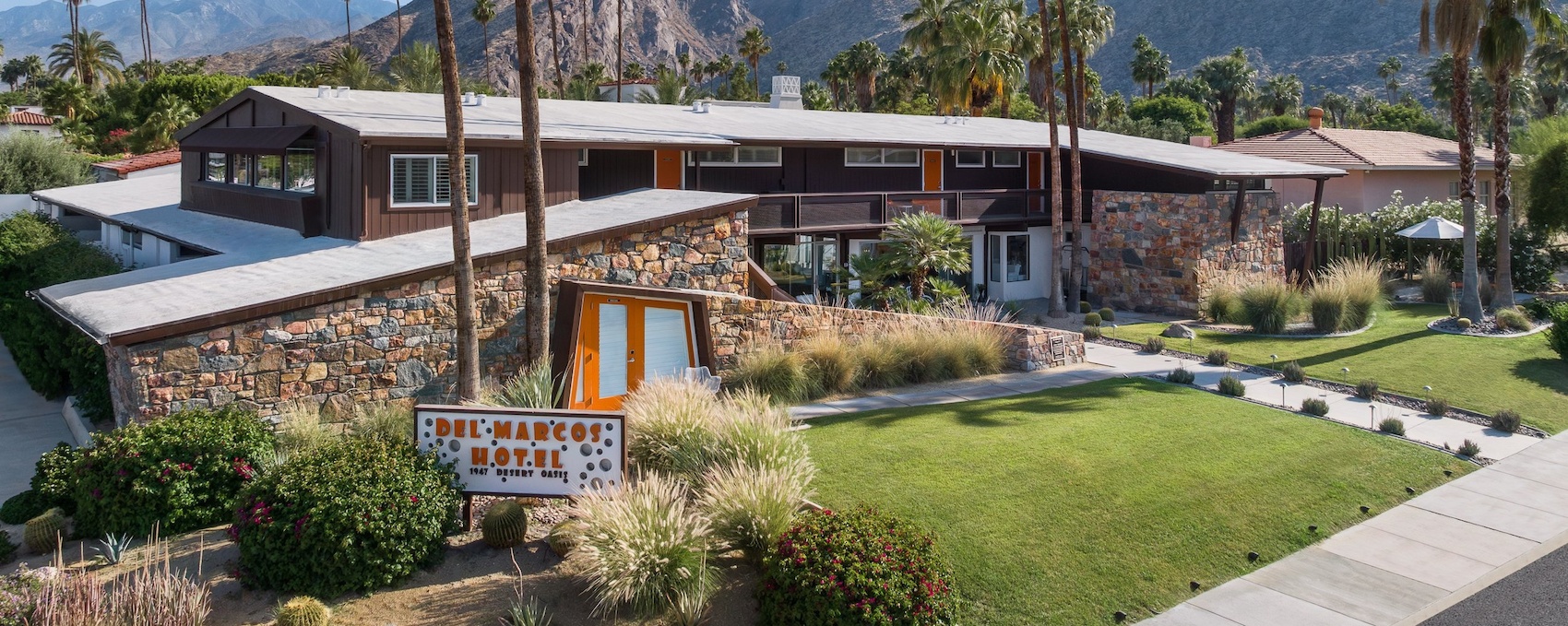 Exterior of the Del Marcos Hotel in Palm Springs with mountains and palm trees in the background