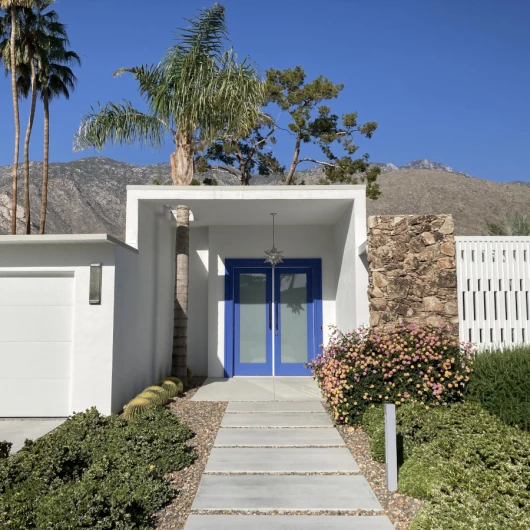 Front walkway leading up to the blue front door of a midcentury modern home in Palm Springs with Mt. San Jacinto in the background