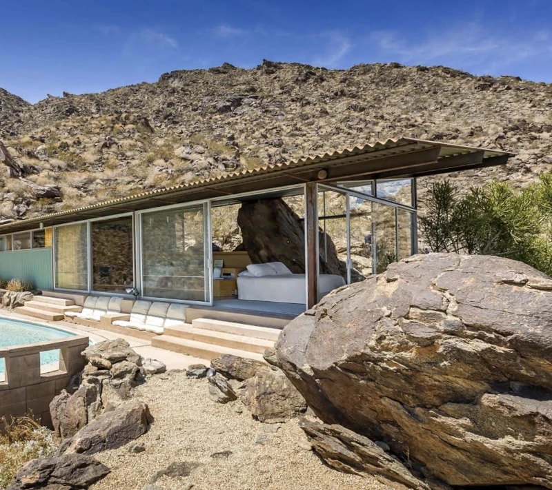 Frey House II with desert landscaping and boulder in the foreground to the right of the pool