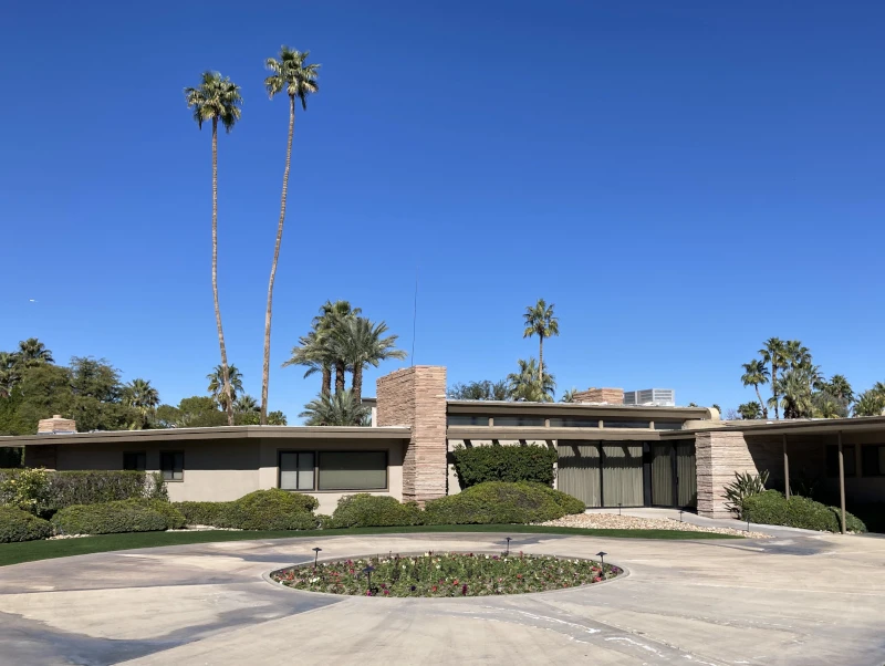Wide view of the Twin Palms Frank Sinatra House in Palm Springs with blue sky and palm trees behind the home